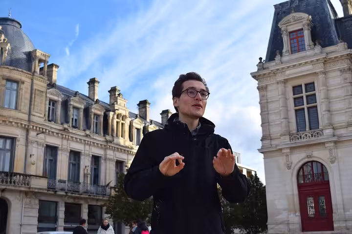 Tour guide explaining the architecture of Poitiers' historic buildings under a clear blue sky.