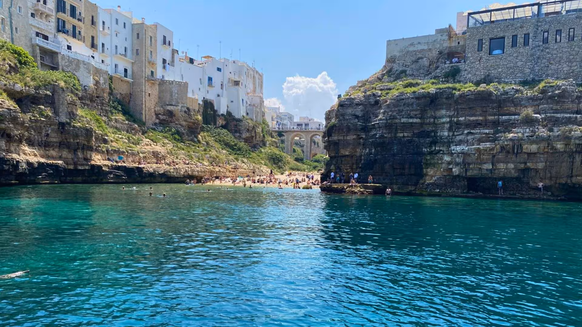 View of a secluded beach surrounded by cliffs and turquoise waters in Polignano a Mare, ideal for a boat tour.