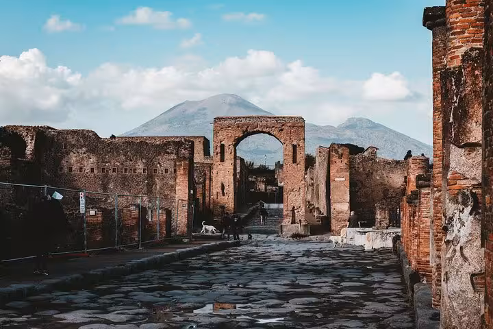View of Pompeii's ancient stone archway with Mount Vesuvius in the background, part of the Sorrento tour.