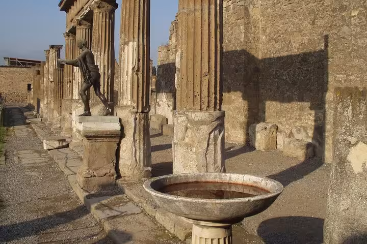 Historic stone columns and statue in Pompeii, highlighting the ancient architecture on the full-day tour from Positano.