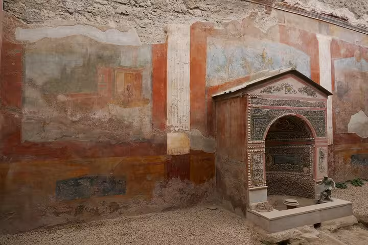 Vibrant frescoed wall and ancient shrine in Pompeii, showcasing rich Roman history on the Sorrento tour.