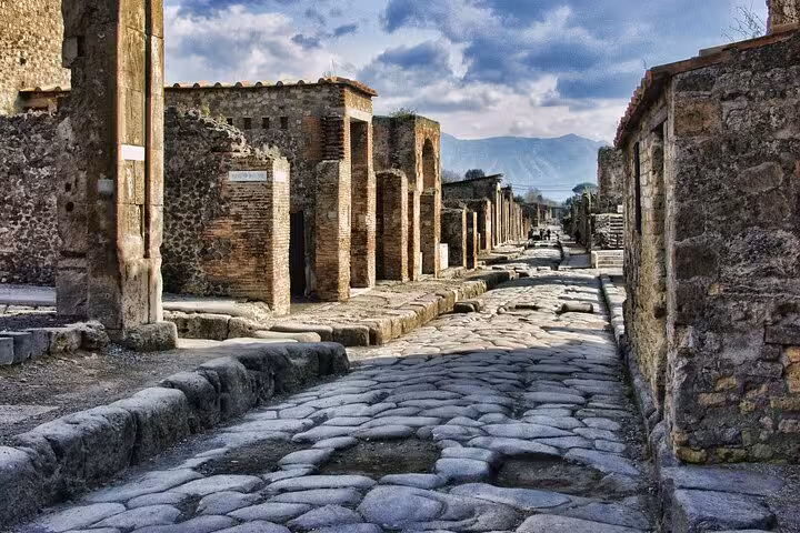 Cobblestone street lined with ancient ruins in Pompeii, offering a glimpse of Roman life on the Sorrento tour.