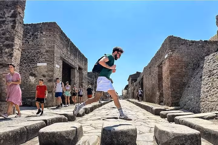 Tourists explore the ancient streets of Pompeii on a guided day trip from Sorrento, showcasing historic Roman ruins.