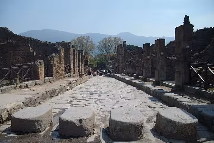 Walk along the historic stone streets of Pompeii featuring ancient ruins, part of a guided tour from Sorrento.