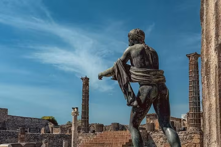Statue amidst ancient columns in Pompeii, offering a glimpse into the rich history on a guided day trip.
