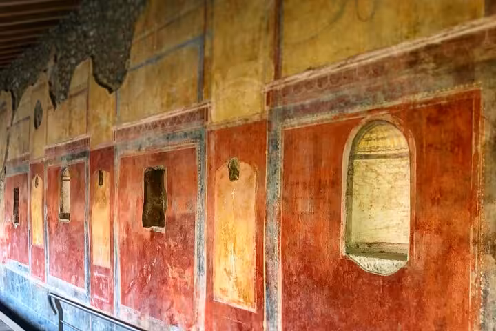 Admire vibrant frescoes inside Pompeii's historic buildings on a small group guided tour from Positano.