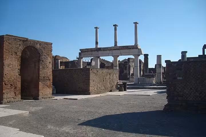 Ruins of Pompeii's ancient architecture with clear blue sky, ideal for guided tours with lunch from Sorrento.