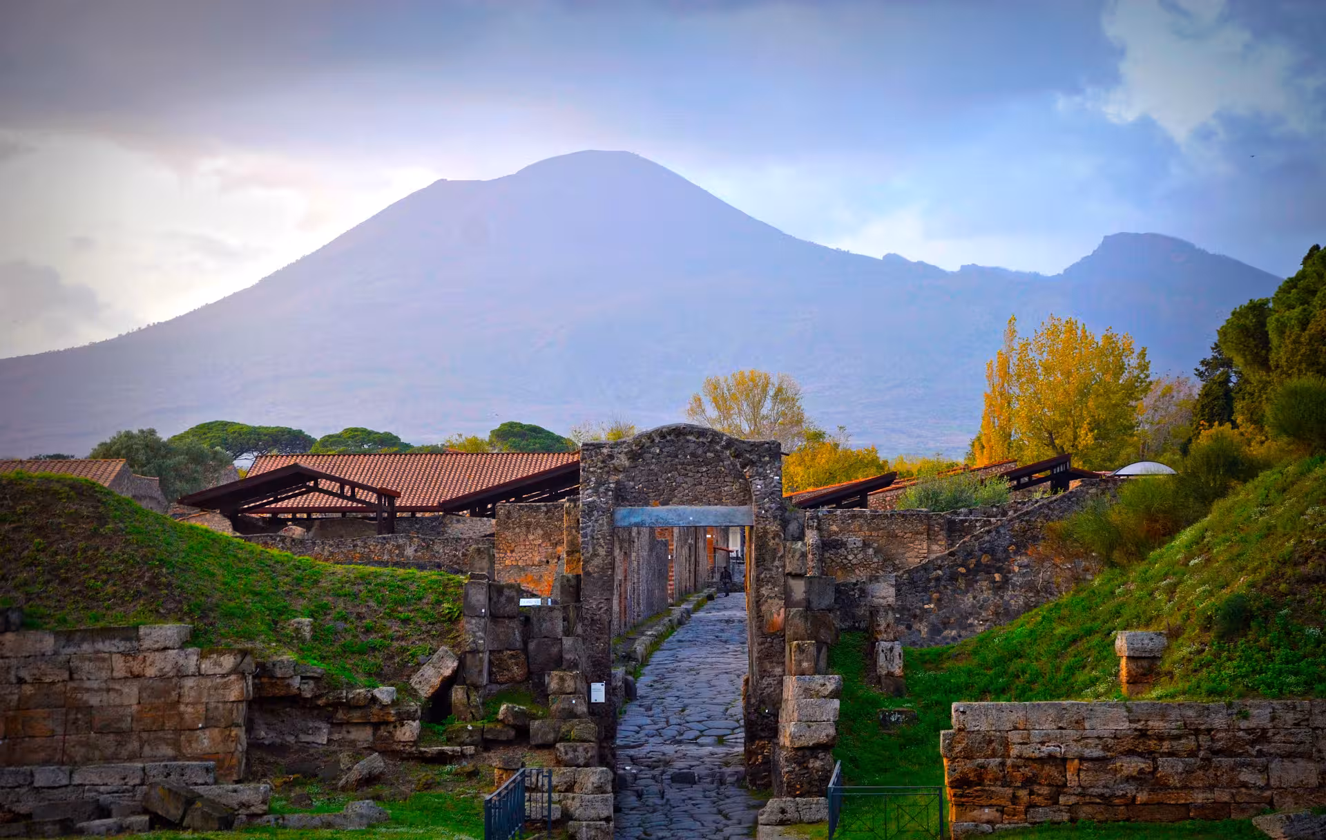 Pompeii ruins stone gateway with Mount Vesuvius backdrop, small group Pompeii Herculaneum wine tour