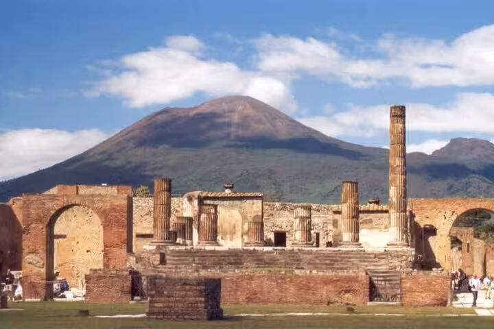 Explore the ancient ruins of Pompeii with Mount Vesuvius towering in the background, offering a skip-the-line tour with lunch.