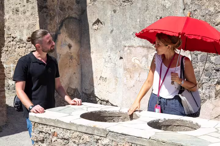 Archaeology expert guiding a private Pompeii tour beside ancient stone counters under the sun near Naples, Italy