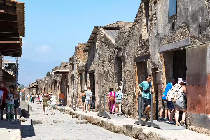 Visitors walking along preserved Roman street and houses in Pompeii during a private archaeology expert-led tour