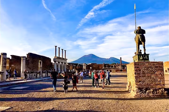 Visitors exploring Pompeii's ancient ruins with Mount Vesuvius towering in the background, ideal for a Positano day trip.