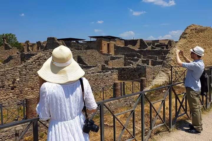 Tourists explore ancient ruins of Pompeii under a sunny sky with skip-the-line convenience and easy lunch included.