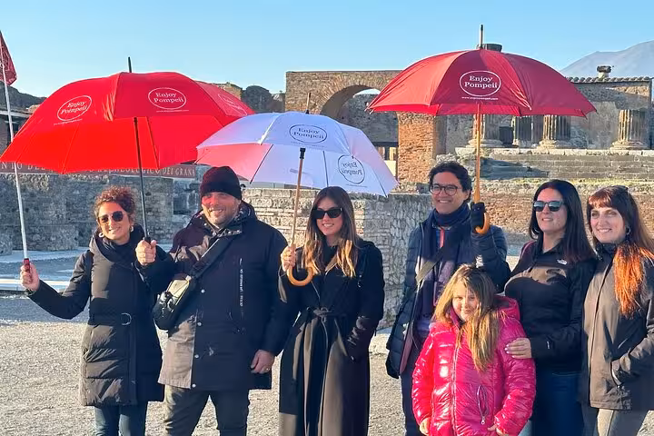 Tour group with umbrellas exploring ancient ruins on a Pompeii tour from Positano.