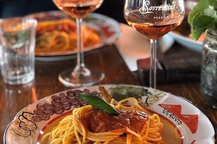 Delicious pasta with tomato sauce and wine on a Vesuvio-themed plate during Pompeii tour lunch from Sorrento.