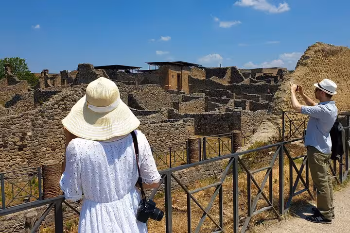 Tourists exploring ancient ruins of Pompeii on a sunny day, capturing memories for the Pompeii and Vesuvius tour.