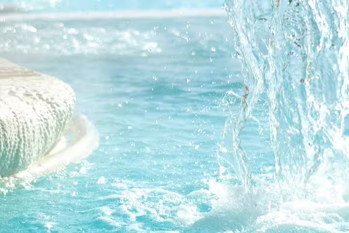 Crystal-clear thermal pool water cascading from a spa fountain at the luxury Pope thermal baths near Rome