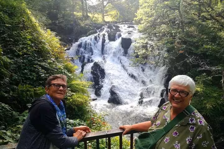 Travellers at a woodland waterfall viewpoint in Snowdonia on the Portmeirion and Castles day tour