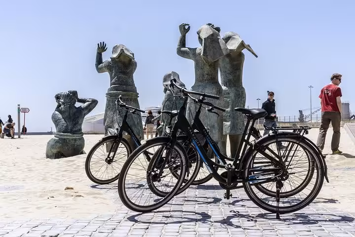 Bicycles parked near unique sculptures at a scenic Porto beach, perfect for a small-group bike tour.