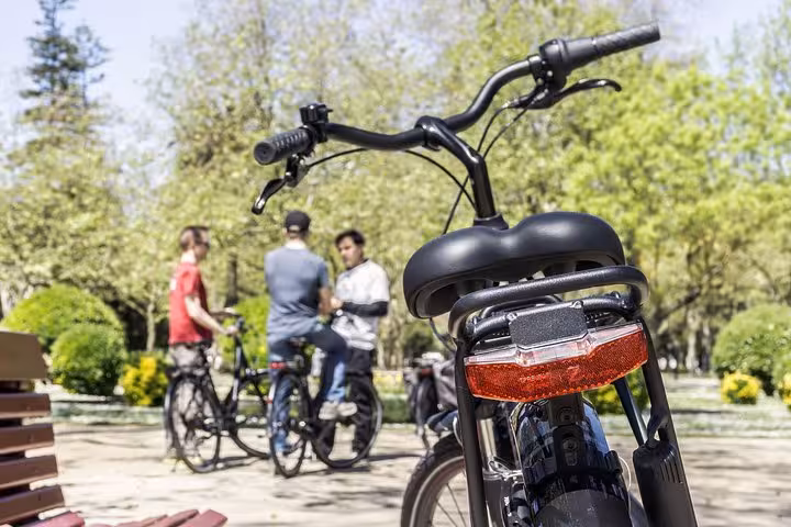 Close-up of a bicycle with a group of friends chatting in a lush Porto park during the small-group bike tour.