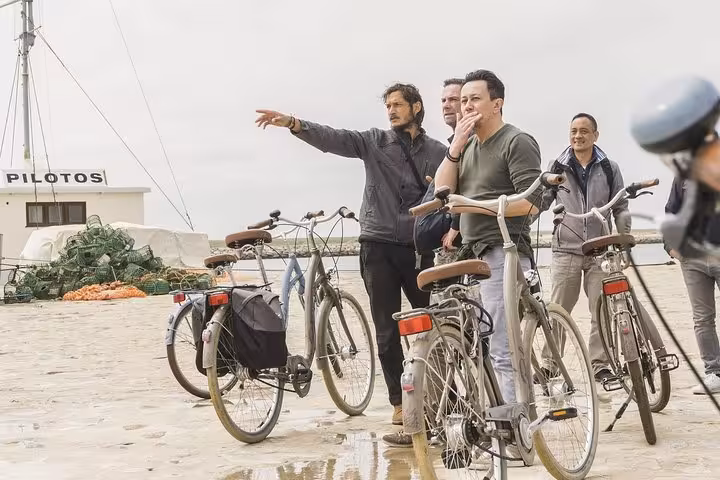 Tour guide pointing out landmarks to a small group of cyclists on a Porto bike tour, creating an engaging experience.