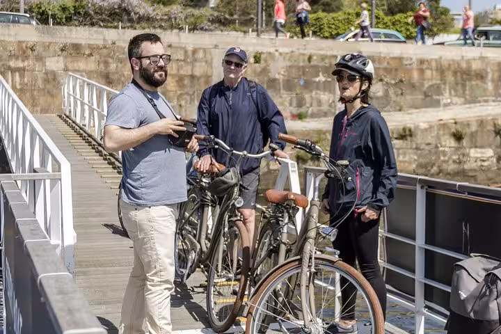 Cyclists on a Porto bike tour stop to admire the riverside views during a sunny day adventure.