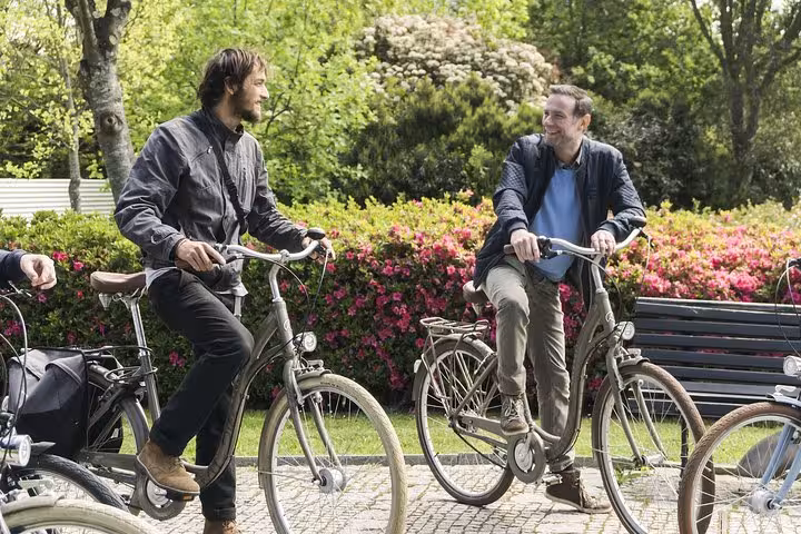Two people enjoy a scenic bike ride through Porto's lush gardens on a 3-hour small-group cycling tour.