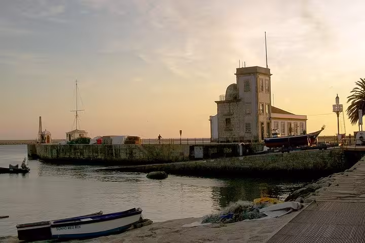 Sunset view of Porto's historic waterfront with boats and a lighthouse, highlighting the tour's picturesque stops.