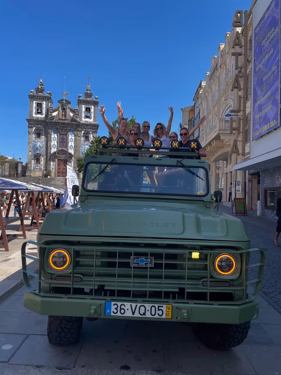 Guests waving from open-top 4x4 in Porto, passing Igreja do Carmo on Douro views city tour