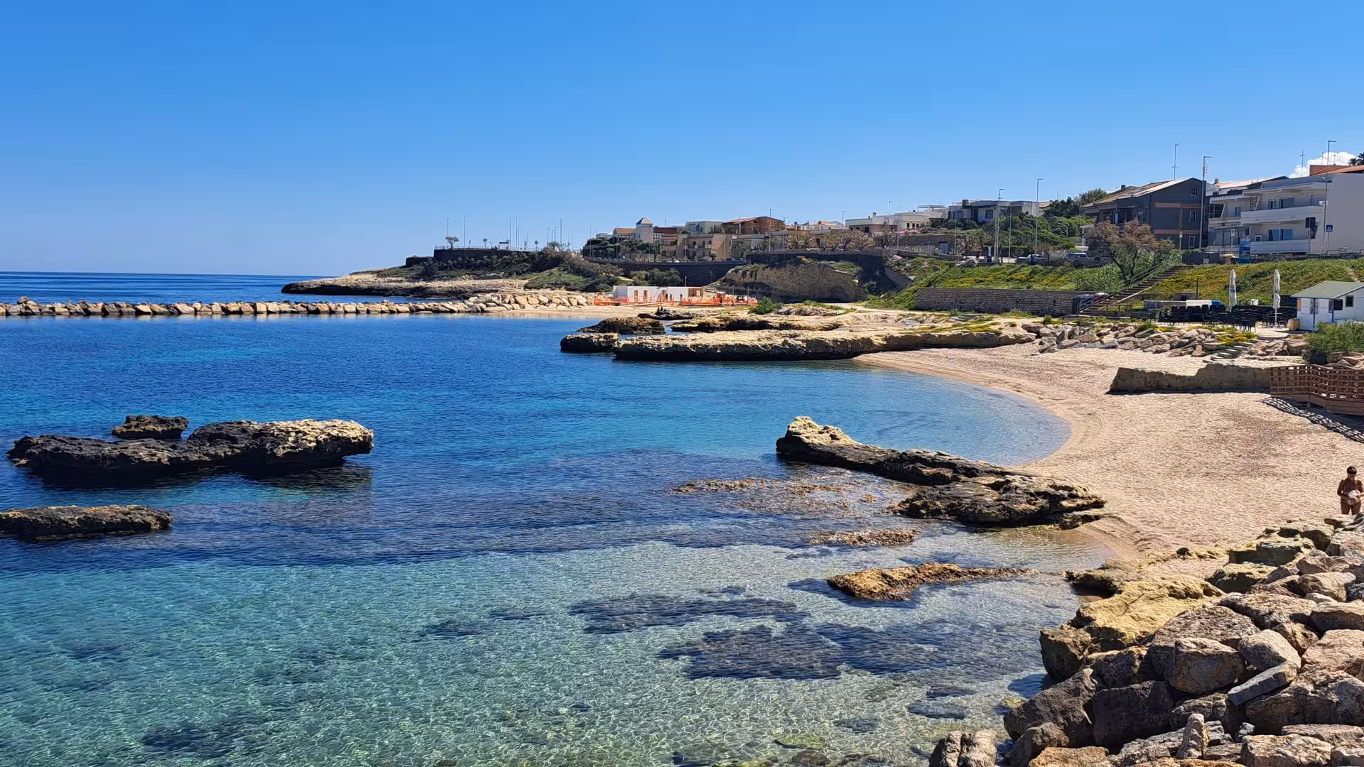 Scenic view of Porto Torres coastline with clear blue waters and rocky shoreline, ideal for diving adventures.