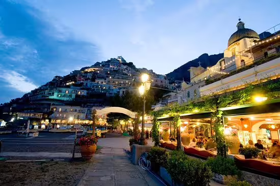 Blue hour in Positano with lit waterfront restaurants and hillside village, From Dusk Till Night immersive tour