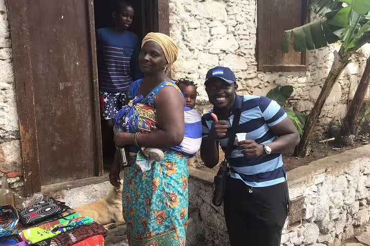 Local vendor and tourist smiling outside a rustic stone house on the Praia by Night cultural tour.