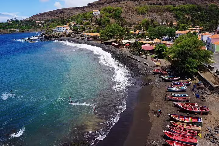 Scenic coastal view of Praia with colorful boats and waves on a sunny day, perfect for Praia by Night experience.