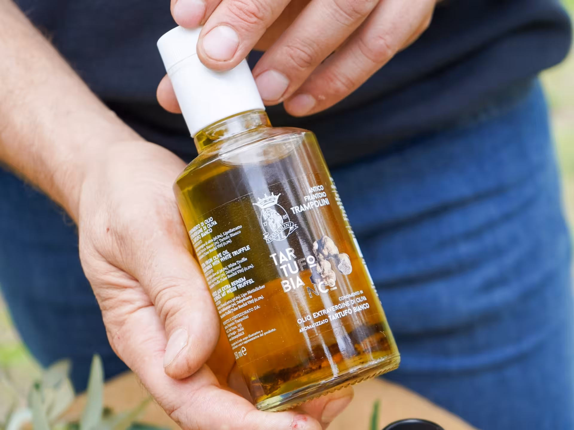 Close-up of a hand holding a bottle of premium olive oil featured in the Perugia olive oil tasting tour.