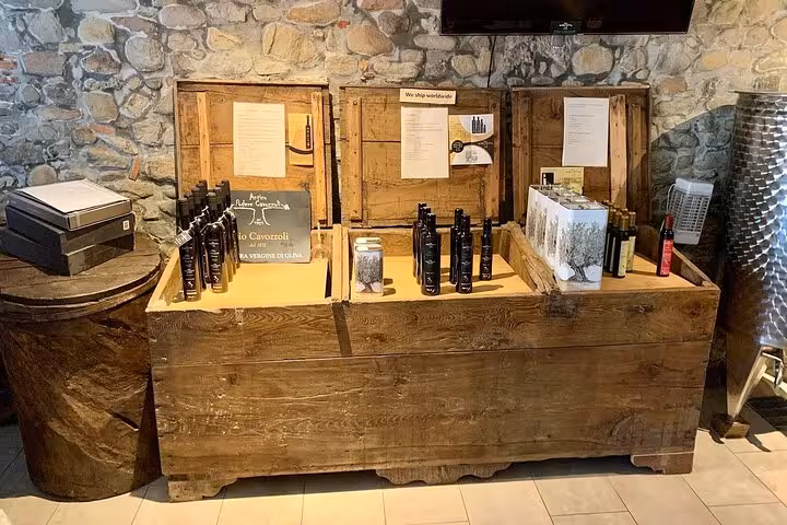 Display of premium olive oil products in a rustic wooden setup against a stone wall, showcasing variety and quality.