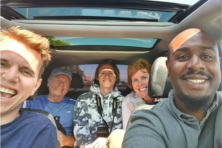Happy travelers in a private car with local guide during a half-day Amsterdam sightseeing city tour