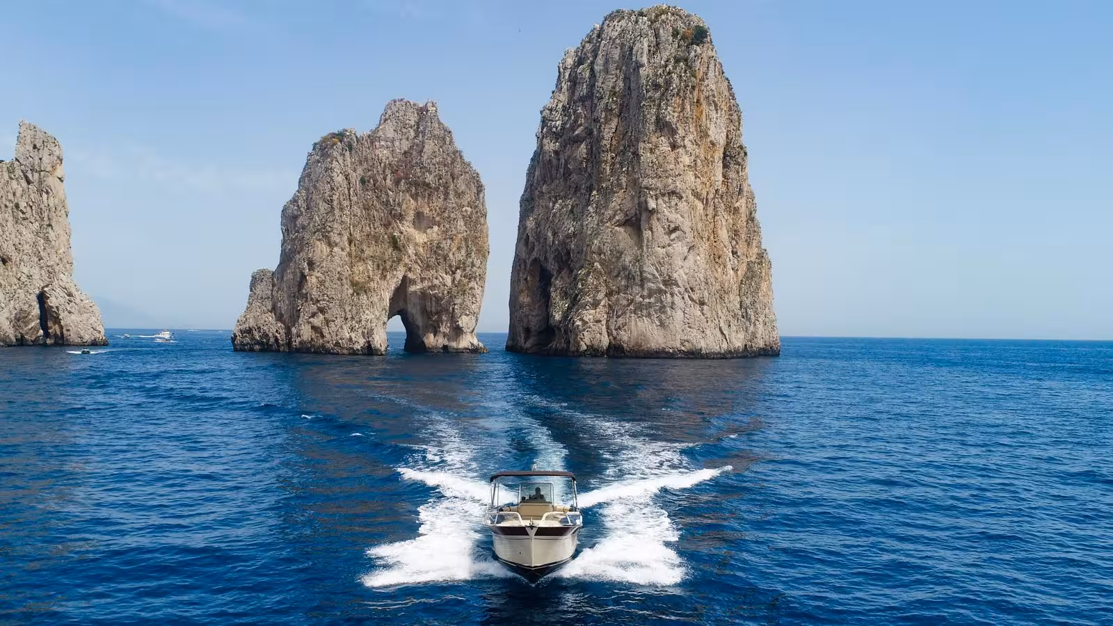 Boat navigating towards the iconic Faraglioni rocks near Capri on an exclusive private tour from Sorrento.