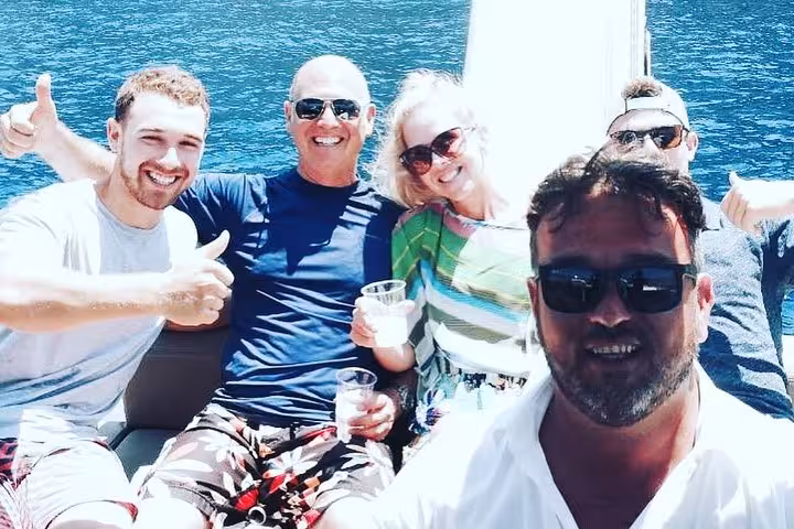 Group of friends enjoying drinks on a sunny private boat tour in Capri with stunning sea views.