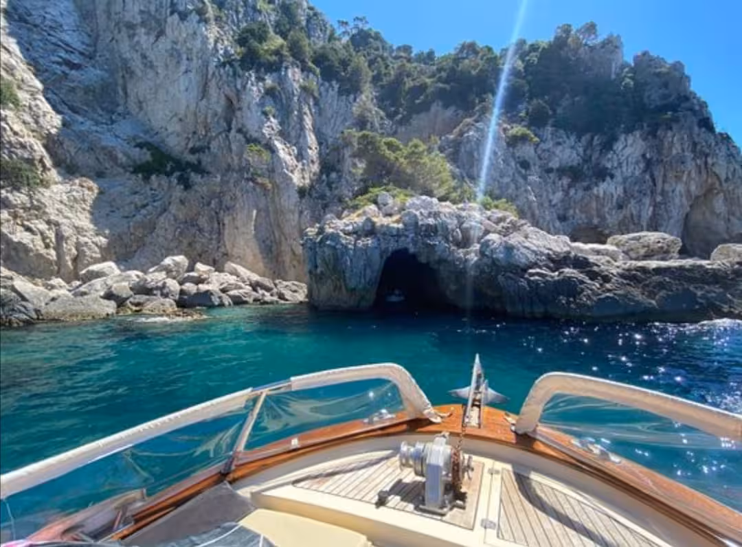 View from a boat approaching a stunning sea cave along the rocky coastline of Capri during a private tour.