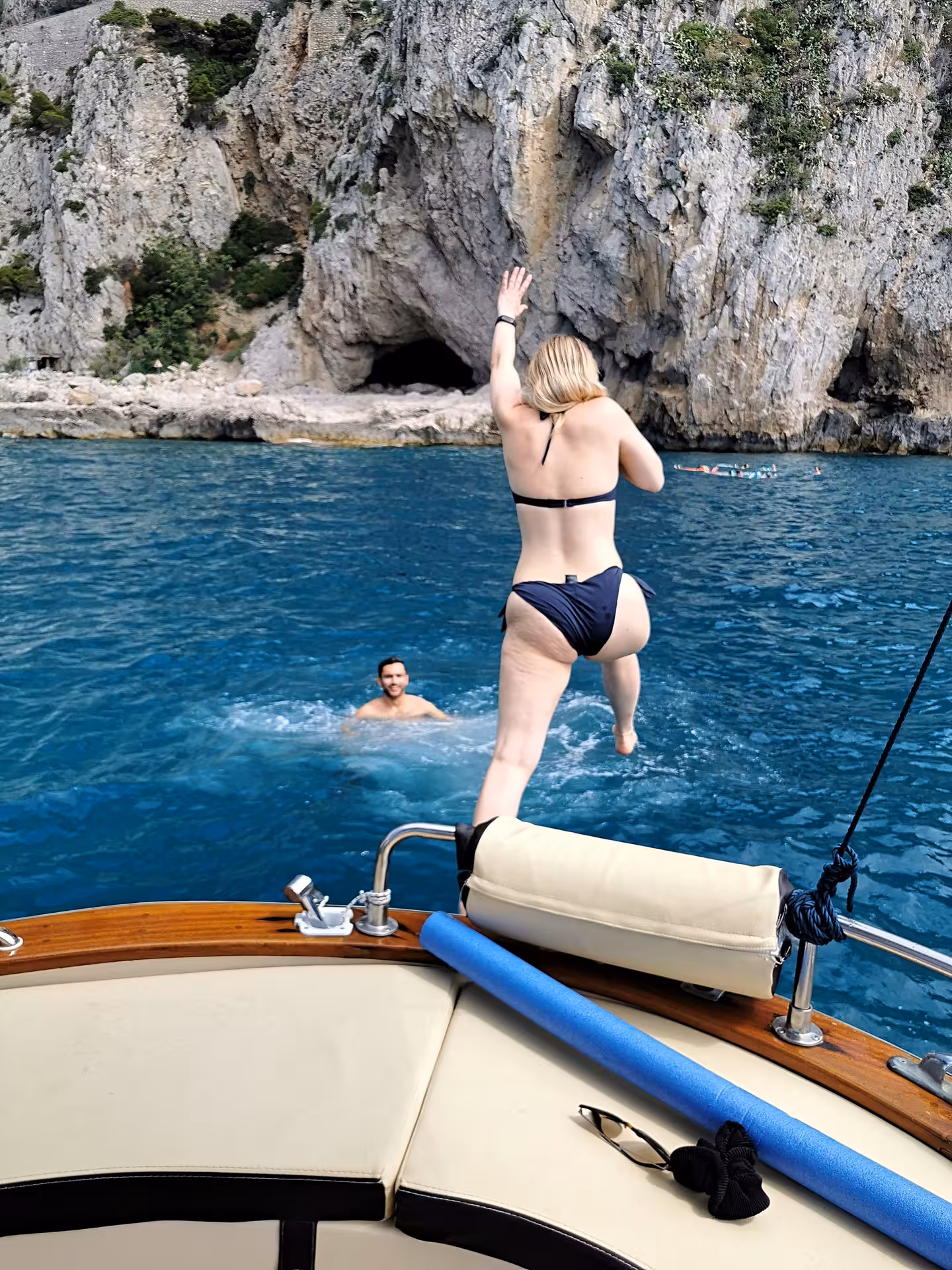 Tourists enjoying a refreshing swim near rocky cliffs on a private boat tour to Capri from Sorrento.