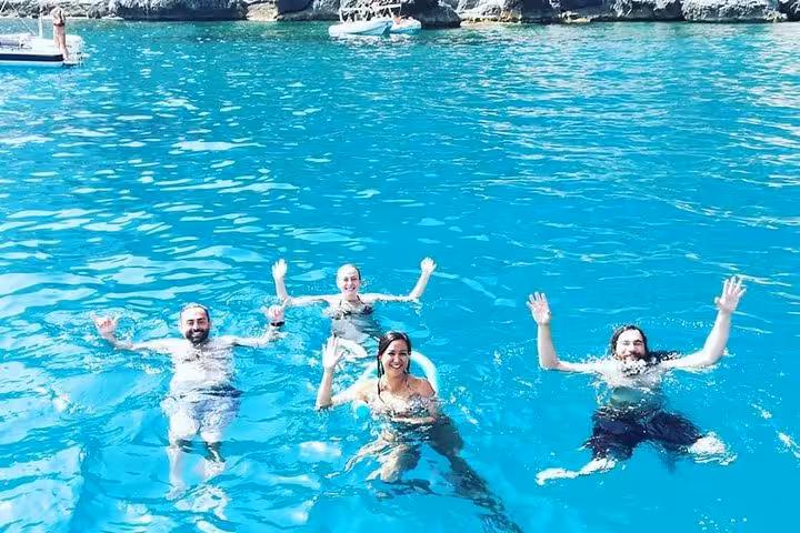 Happy group of friends swimming in crystal-clear waters on a private Capri boat tour from Sorrento.