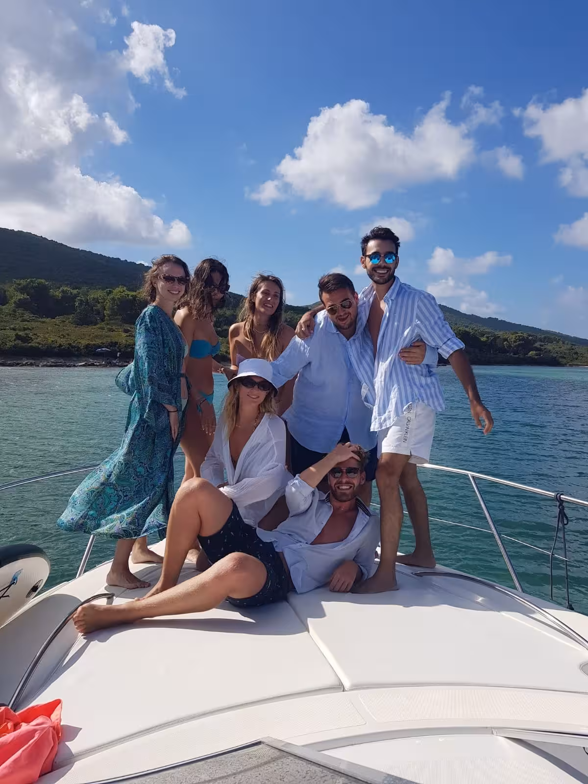 Happy group posing on a private boat tour in the crystal-clear waters of the Gulf of Alghero.