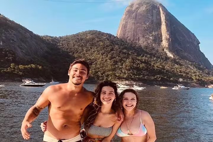 Group of friends on a private boat tour smiles with Sugarloaf Mountain in the Rio skyline.