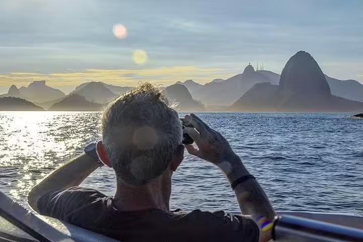 Traveler on a private boat tour enjoys panoramic views of Rio's iconic Sugarloaf Mountain at sunset.