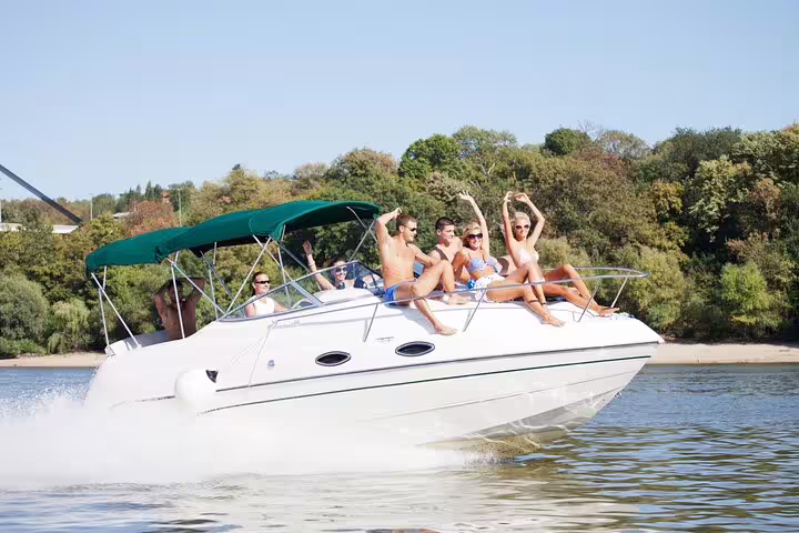 Group enjoying a lively day on a private boat tour in Santos with lush greenery in the background.