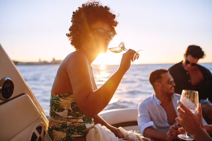 Group enjoying drinks on a private boat tour in Santos during a stunning sunset.