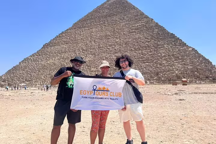 Travelers with tour banner in front of the Great Pyramid of Khufu on private Cairo day tour and GEM visit