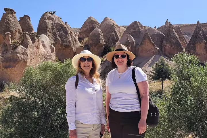Visitors smiling in front of unique fairy chimneys during a best-seller private Cappadocia tour from hotel and airport.