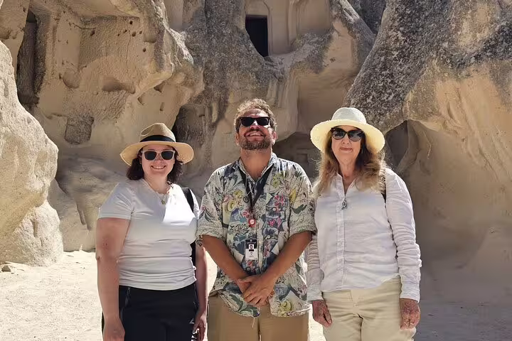 Tourists exploring ancient rock formations on a private Cappadocia tour from hotel and airport, enjoying the historical ambiance.