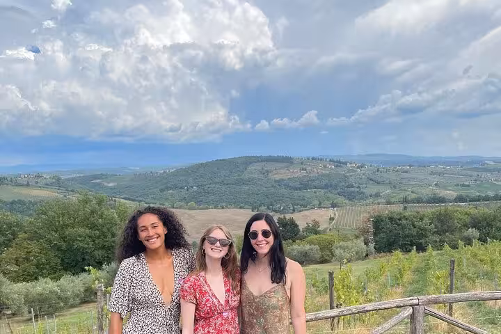Three friends enjoying a private tour in Chianti with a backdrop of lush vineyards and scenic hills.
